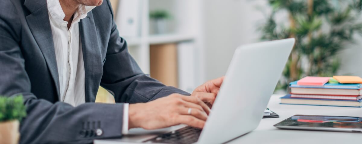 Business professional working at a laptop while reviewing business continuity and disaster recovery information