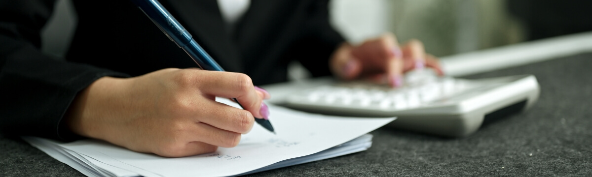 Business professional reviewing IT cost reduction notes with a calculator and paperwork