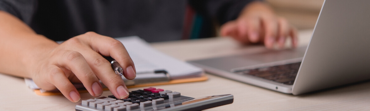 Business owner reviewing IT costs on a calculator and laptop before a small business IT spending audit