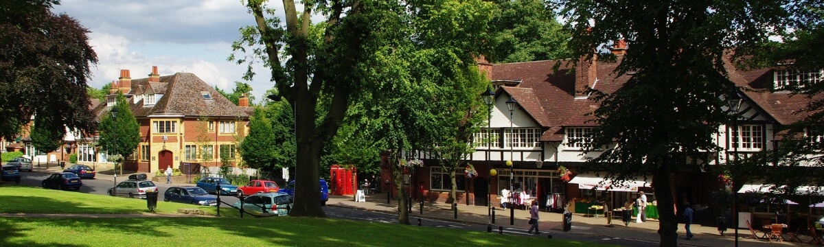 View of Bournville Village Green in Birmingham, showing local shops, trees and surrounding buildings