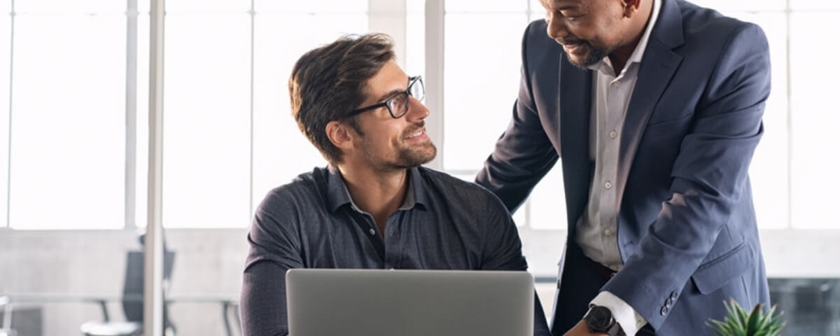 IT support specialist helping a colleague with a laptop issue in a West Midlands office