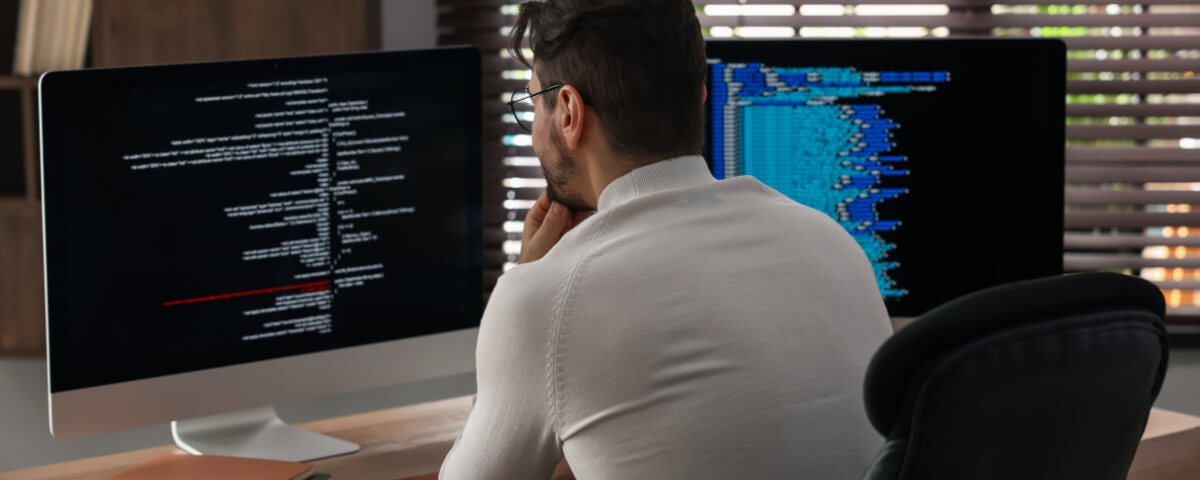 IT professional monitoring systems on dual screens, representing a properly managed remote IT setup for hybrid and distributed teamsIT professional monitoring systems on dual screens, representing a properly managed remote IT setup for hybrid and distributed teams