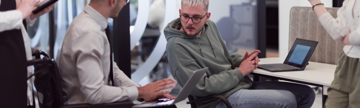 Tech professionals collaborating on laptops in a modern workspace, illustrating how outsourced IT service providers work with UK businesses