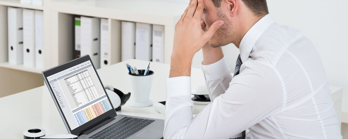 Small business employee looking stressed while reviewing problematic data on a laptop screen