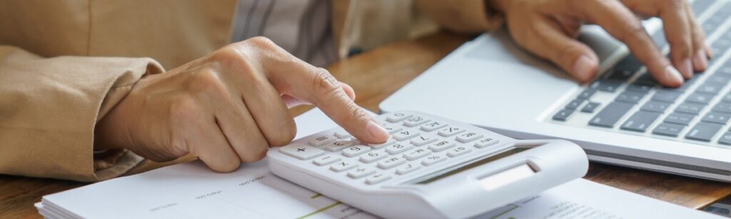 Small business owner calculating UK IT support costs beside a laptop and business paperwork