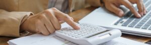 Small business owner calculating UK IT support costs beside a laptop and business paperwork