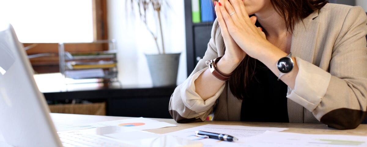 Business owner sitting at a desk looking worried while facing a laptop during an IT disruption